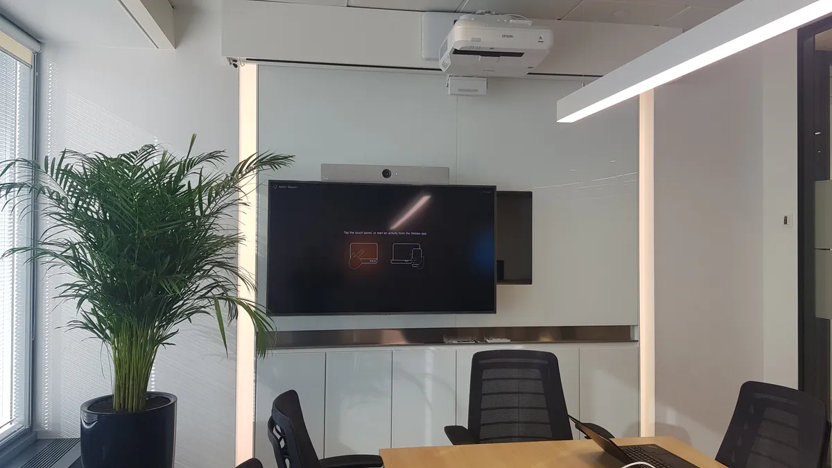 Sala de reuniones con pantalla profesional y sistema de videoconferencia