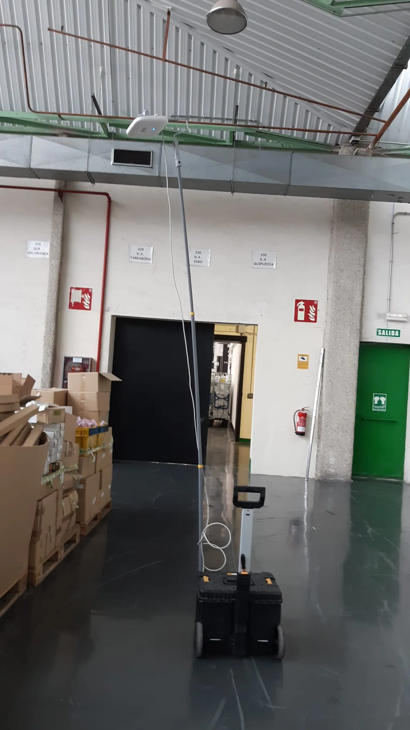 Pasillo de almacén con estructuras metálicas que generan sombras de cobertura Wi-Fi